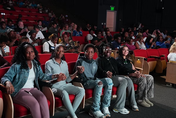 A smiling audience watching young founders at Youth Pitch Day